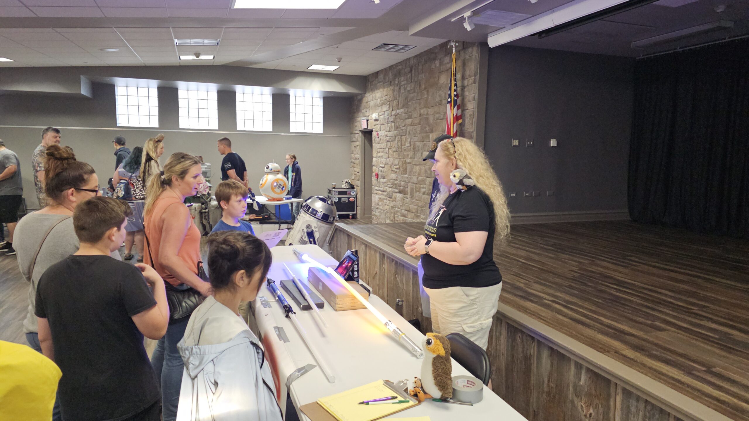 Lady behind table with lightsabers with people