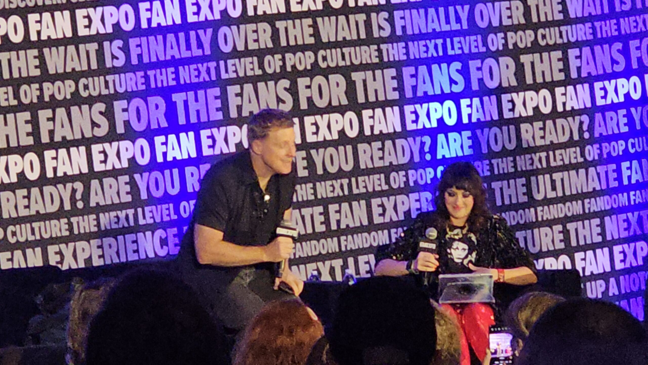 Alan Tudyk sitting down next to moderator